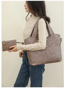 Detail of large brown faux leather tote with matching small zipper pouch and decorative stitching