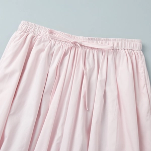 Detail of light pink elastic waistband with a matching drawstring bow on cotton trousers