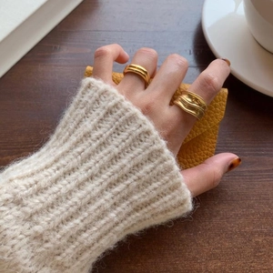 Detail of 925 silver double-layered gold ring and wavy textured band worn with a warm sweater