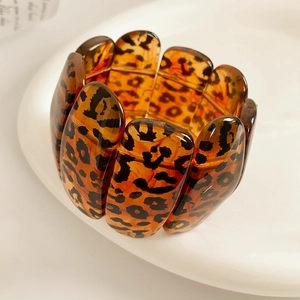 Détail du large bracelet en résine léopard aux tons ambrés et structure élastique