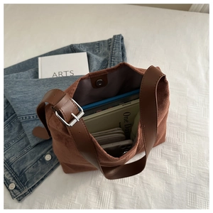 Brown faux suede tote bag with large capacity, shown on white textured bedding