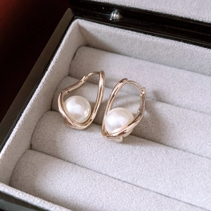 Macro shot of gold twist earrings with white pearls in a velvet lined jewelry box