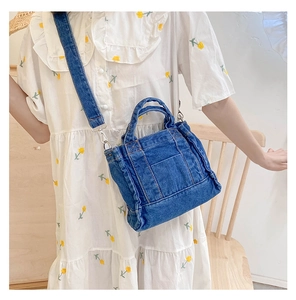 Close-up of blue denim crossbody bag with adjustable strap worn over floral dress
