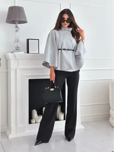 Détail d'une cape en laine grise avec ceinture fine et pantalon large noir élégant