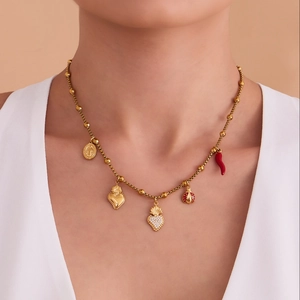 Gouden roestvrijstalen ketting met hartje, lieveheersbeestje en hoorn op vrouwelijk model