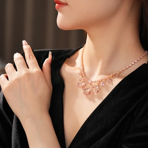 Close-up of pink zircon flower pendant necklace with golden chain on model's neckline