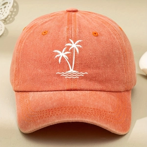 Detailed macro view of white palm tree embroidery on orange washed cotton baseball cap