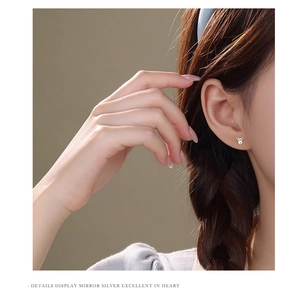 Close-up of polished S925 sterling silver bow earrings with sparkling zircon on ear