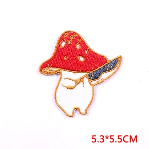 Detailopname van paddenstoelpatch met rode hoed en goud borduursel voor kleding