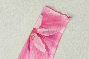 Détail du tissu en maille à imprimé fleuri rose avec bords volantés et texture translucide