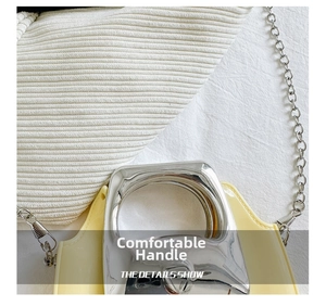 Detail showing the shiny silver metal handle and fine chain of the cream crossbody bag