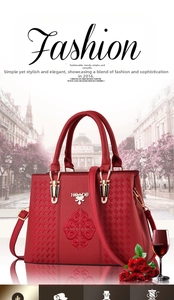 Detail of red leather tote bag with elegant floral embroidery and gold brand plaque