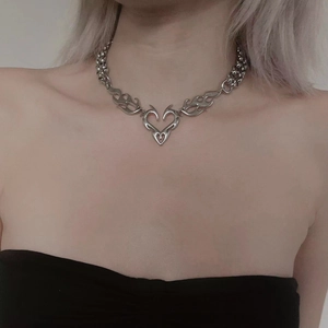 Close-up of a silver heart flame necklace in punk Y2K style worn by a female model