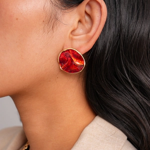 Close-up of vintage style round red enamel earrings with gold textured metallic edges