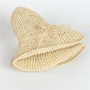 Dettaglio cappello di paglia beige pieghevole con trama all'uncinetto e fiocchetto