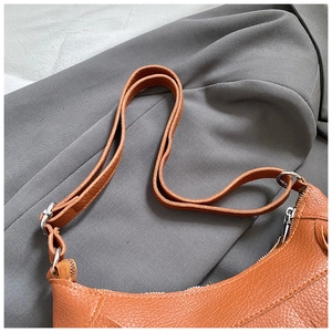 Detail of orange-brown pebble leather shoulder bag with silver ring hardware and strap