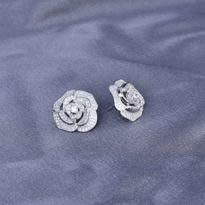 Detailed view of silver rose-shaped stud earrings with sparkling pavé micro-insets