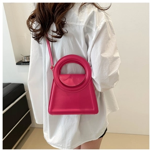 Detailed view of a bright rose pink tote bag with round handle worn by a model