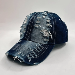 Detailed close-up of distressed denim baseball cap with vintage frayed holes and white stitching