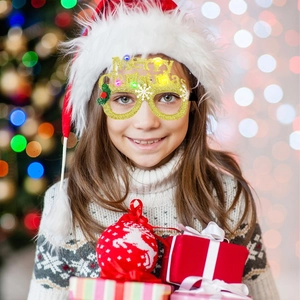 Close-up of a child wearing glowing gold glitter Merry Christmas LED glasses for holiday parties