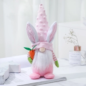 Pink Easter gnome plush with long rabbit ears and a carrot on a bright home desk