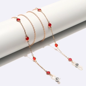 Detail of a handmade gold eyewear chain with red crystal beads and silicone loops