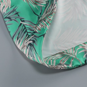 Detailed close-up of tropical palm leaf print and satin fabric stitching for summer dress