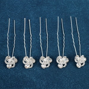 Close-up of five silver U-shaped hair pins with floral rhinestone crystals on blue velvet