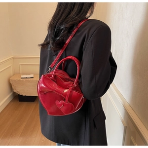 Gros plan d'un sac à main cœur rouge vif avec un grand nœud et fini brillant