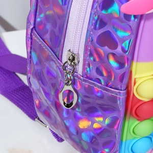 Detail of silver zipper and rainbow pop-it silicone on purple heart texture backpack