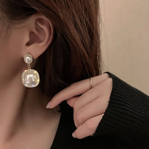 Detailansicht eleganter goldener Ohrhänger mit glänzenden Perlen und Strasssteinen