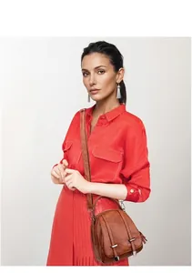 Brown vintage faux leather crossbody bag worn by a model in a red dress with studio lighting