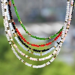 Close-up of layered colorful faceted crystal bead necklaces with golden hexagonal spacers