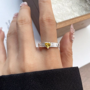 Detailed view of a silver ring featuring a heart-shaped yellow gemstone and ornate engraving