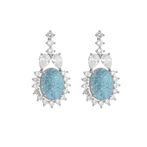 Detailed close-up of light blue oval gemstone earrings with sparkling halo and silver plating