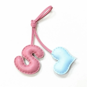 Detail of pink leather letter S and blue heart charms with handmade stitching