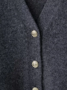 Détail du cardigan en maille gris foncé avec boutons dorés ancrés et texture douce