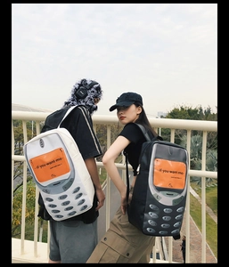 Outdoor shot of couple wearing black and white backpacks in retro phone design