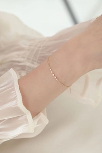 Primer plano de una pulsera de plata bañada en oro de 14k con cinco circones en la muñeca