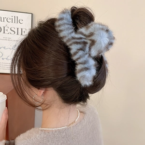 Detailed view of large blue and brown tiger print plush hair claw clip in a bun hairstyle