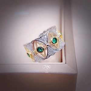 Macro detail of vintage hollow ring with green emerald stones and white zircons
