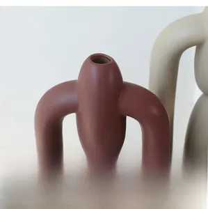 Close-up of matte ceramic vase showing smooth textured finish and U-shaped tubular design