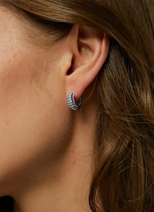 Close-up of silver-tone ribbed croissant hoop earring worn by a model for a stylish look
