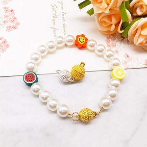 Detail of colorful fruit charms and magnetic clasps on pearl beaded bracelets
