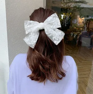 Elegant white lace bow hair clip with embroidery on a model for sweet bridal styles
