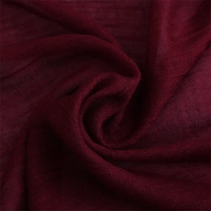 Detailed macro shot of dark red cotton linen fabric texture with soft woven folds