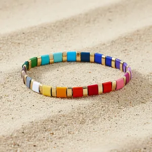 Macro shot of colorful enamel elastic bracelet on beach sand texture for summer resort style