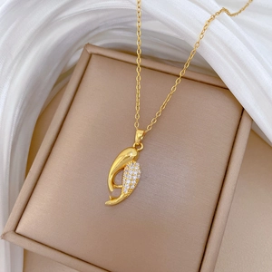 Gros plan d'un collier en titane doré avec plumes en zircon dans un écrin à bijoux beige