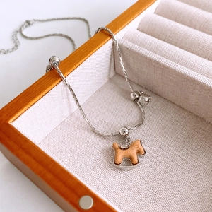 Détail d'un pendentif cheval à bascule en bois avec chaîne argentée dans un coffret