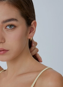 Close-up of gold lightning hoop earrings with sparkling cubic zirconia on a model